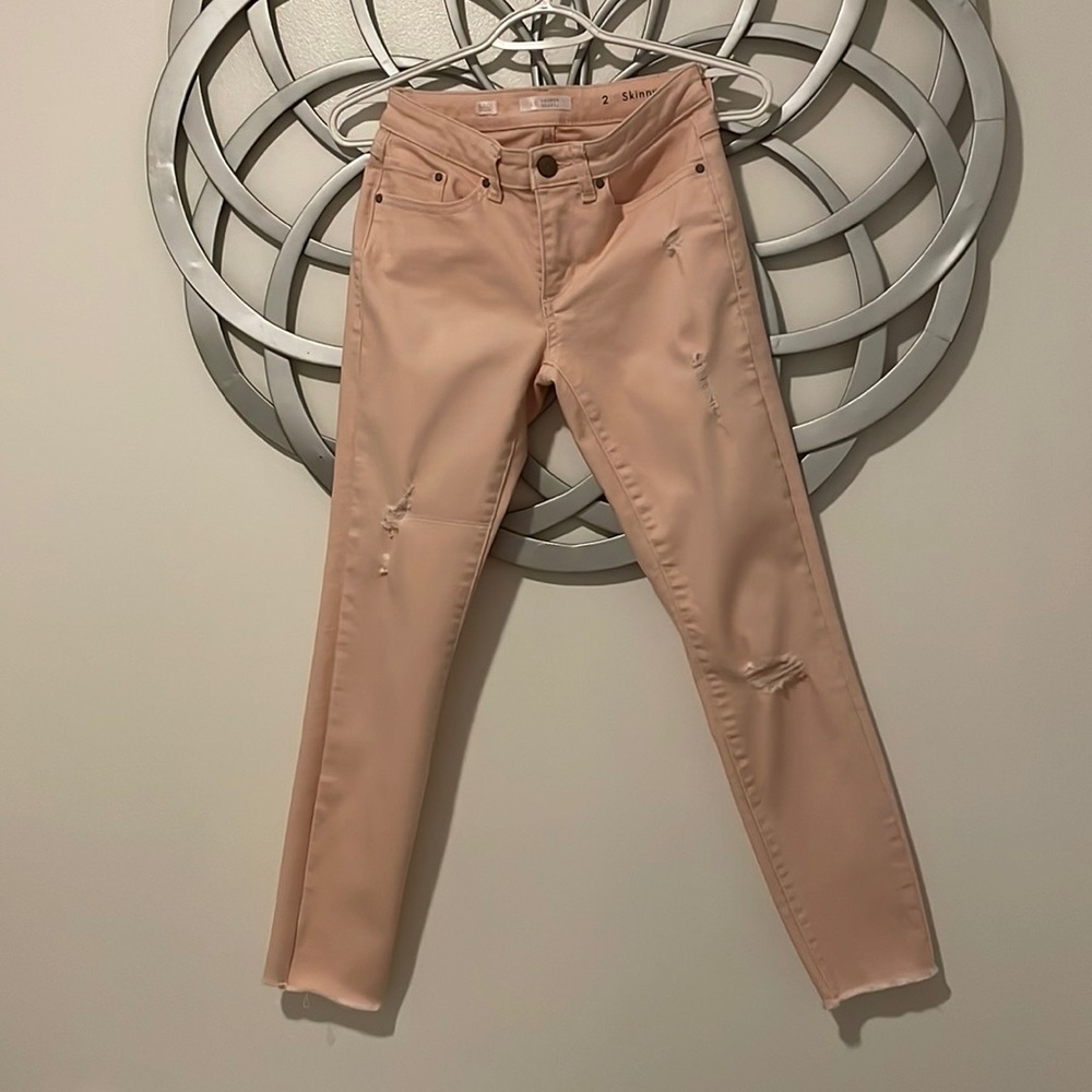 Peachy pink distressed skinny jeans.